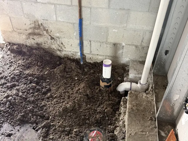 Plumbing stub and cleanout set into the fill along a block wall