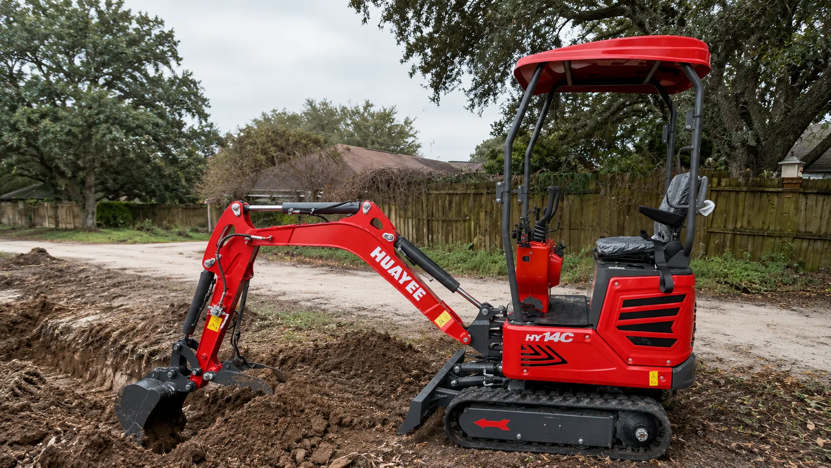Compact excavator cutting into soil and shaping ground on a job site