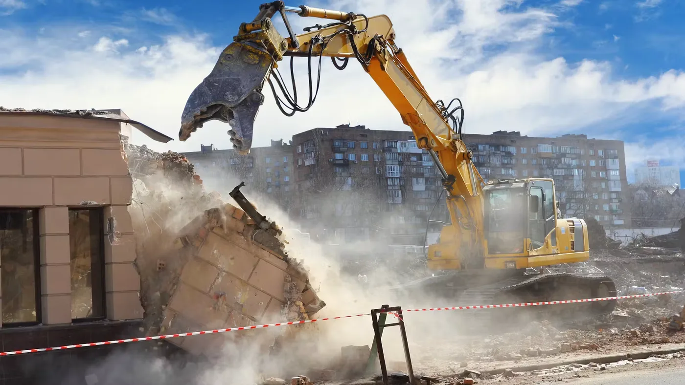 Excavator with a grapple demolishing a building